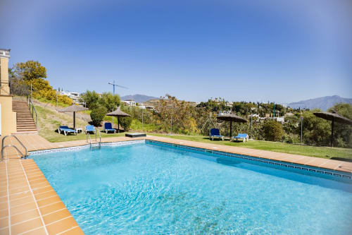 Piscina del BH Marbella con tumbonas, sombrillas y vistas a la sierra de Marbella, España