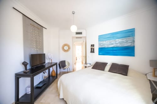 Dormitorio moderno en hotel BH Marbella con cama matrimonial, televisor, obra de arte con vista al océano y decoración contemporánea