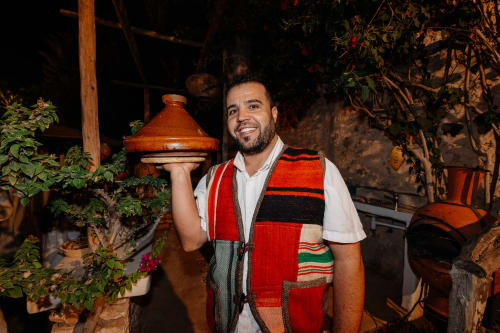 Homme tenant un tajine traditionnel au Riad Eucalyptus, hôtel ethnique à El Ghazouane, Maroc