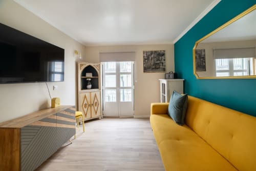 Apartamento de 2 quartos no Bica Mini Hostel, Lisboa com sofá amarelo, parede azul-petróleo, TV e zona de refeições