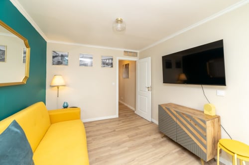 Apartamento moderno com 2 quartos no Bica Mini Hostel em Lisboa com sofá amarelo, TV de ecrã plano e parede de destaque em verde-azulado