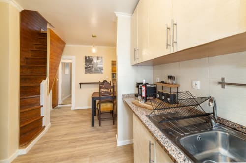 Cozinha moderna com bancada em granito, pia em aço inoxidável e área de refeições no apartamento de 2 quartos do Bica Mini Hostel