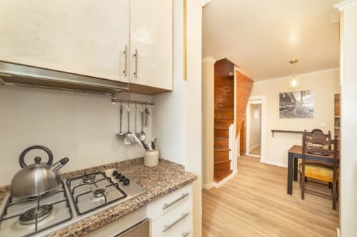 Cozinha moderna com bancada em granito, fogão a gás e chaleira em aço inoxidável no apartamento de 2 quartos do Bica Mini Hostel