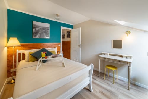 Apartamento luminoso com 2 quartos no Bica Mini Hostel em Lisboa, com parede de destaque em azul-petróleo, cama de madeira, secretária e comodidades modernas