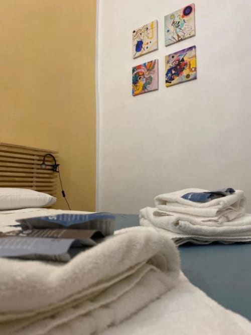 Camera dell'Affittacamere Bronze Horse a Firenze con arte moderna colorata, pareti gialle e biancheria piegata sul letto