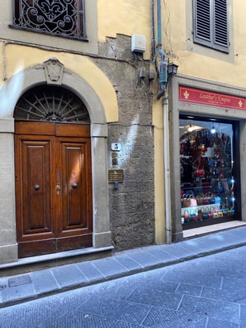 Ingresso di via storica fiorentina con porta in legno e negozio di articoli in pelle vicino all'Affittacamere Bronze Horse