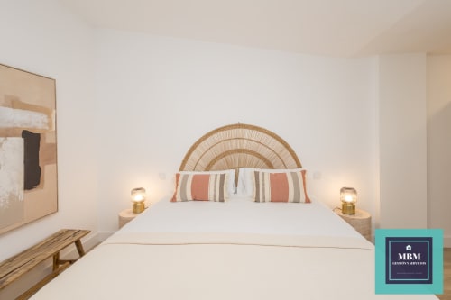 Dormitorio moderno en MBM Hostel de Arucas con cabecera tejida, almohadas rayadas y lámparas de mesita de noche