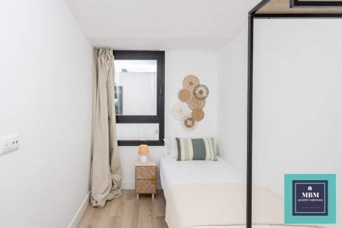 Habitación moderna en el hostal MBM Arucas con cama dosel, arte tejido en la pared, ventana con cortinas y mesita de noche de madera