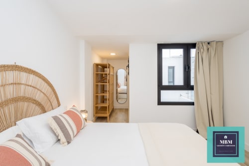 Dormitorio moderno en apartamento Dúplex Albareda del hostel MBM en Arucas con cabecero tejido, almohadas rayadas y vistas a la ciudad