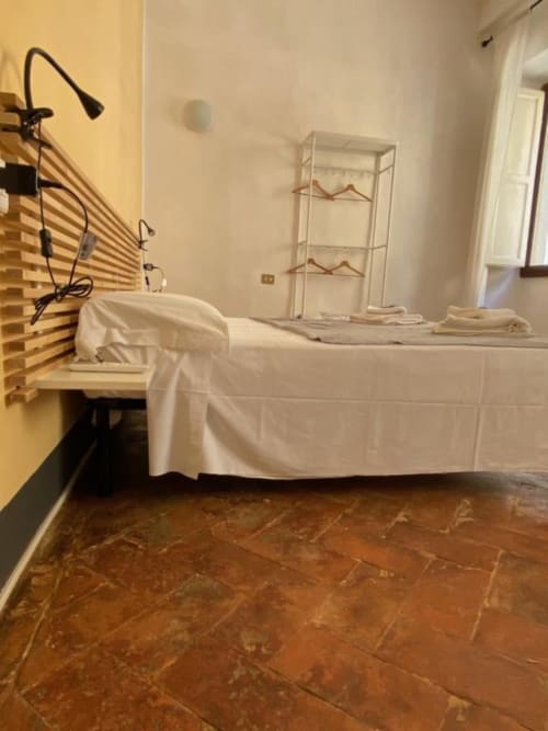 Camera da letto al Bronze Horse Affittacamere di Firenze con letto, lampada da scrivania, mensola in vetro e pavimento in cotto