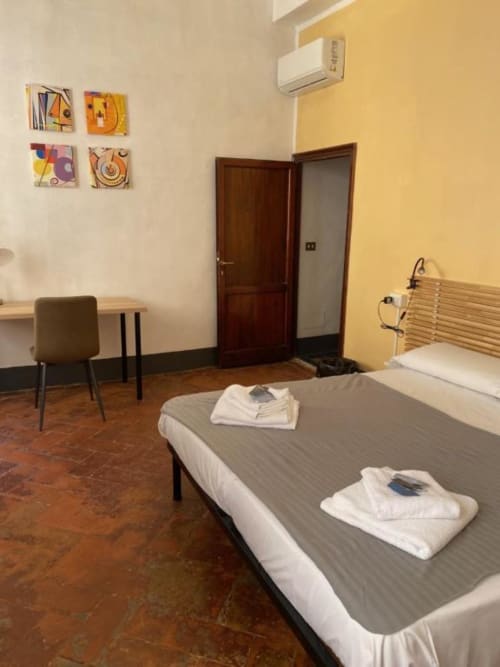 Contemporary bedroom at Bronze Horse Affittacamere in Florence with twin beds, colorful artwork, and modern amenities