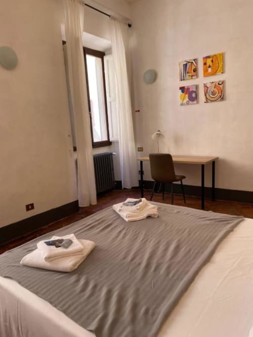 Bright bedroom at Bronze Horse Affittacamere in Florence with bed, desk, colorful wall art, and modern furnishings