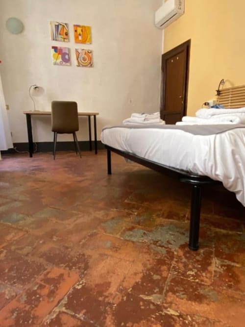Modern bedroom at Bronze Horse Affittacamere in Florence with bed, desk, terracotta floor, and colorful wall art