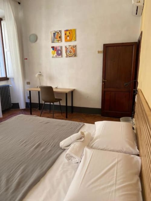 Spacious bedroom at Bronze Horse Affittacamere in Florence featuring bed, desk, and colorful wall art