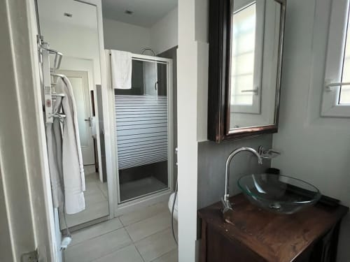 Modern bathroom in Padova B&B apartment with glass shower enclosure, dark sink vanity, and large mirror