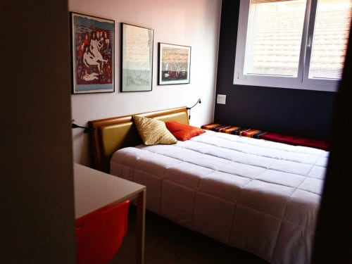Modern bedroom at Il Maestrale B&B in Padova with wooden bed frame, colorful pillows, framed artwork, and contemporary