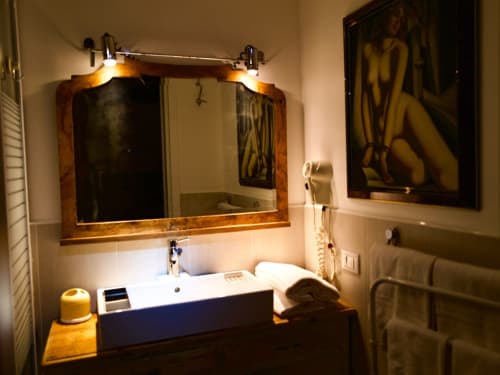 Modern bathroom at Il Maestrale B&B in Padova with wooden framed mirror, white sink, and ambient lighting