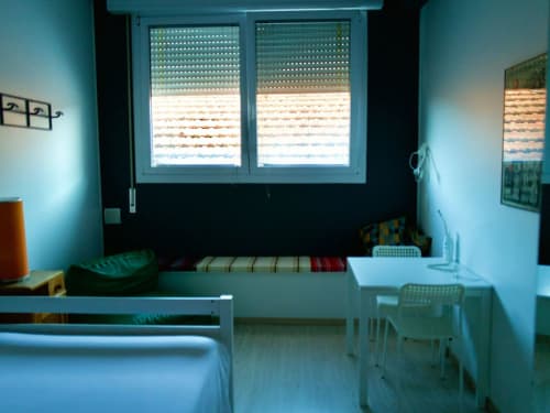 Compact apartment bedroom at Il Maestrale B&B in Padova with bed, desk, window blinds, and minimal furnishings