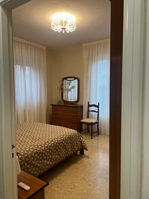 Camera da letto accogliente nella villa Tales of Abruzzo con letto, cassettone in legno con specchio, sedia e tende trasparenti ad Atessa, Italia