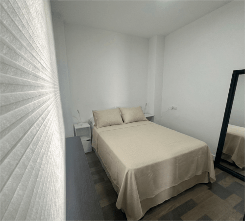 Dormitorio moderno en Living Sur, Sanlúcar de Barrameda, con cama queen, ropa de cama beige, paredes blancas y cortinas translúcidas