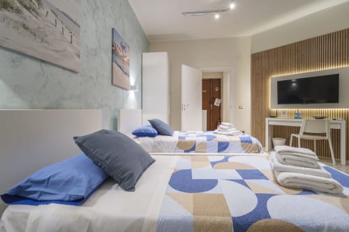Camera da letto moderna nell'appartamento di Messina con letti gemelli, biancheria blu decorata, TV a schermo piatto e dettagli in marmo