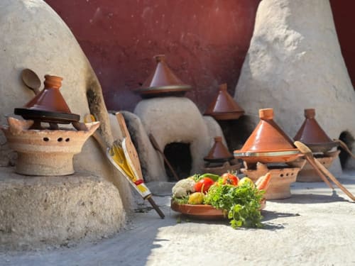 Préparation traditionnelle de tajine marocain au Riad Eucalyptus avec poteries en terre cuite et légumes frais à El Ghazouane