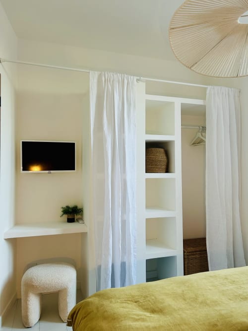 Modern bedroom at Casa di Bastia, Bastia with built-in shelving, mounted TV, cream stool, and yellow bedding