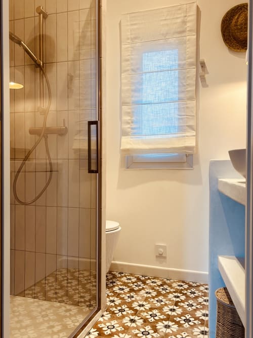 Modern bathroom with walk-in shower, decorative tile floor, and window with blue blinds at Casa di Bastia, Bastia