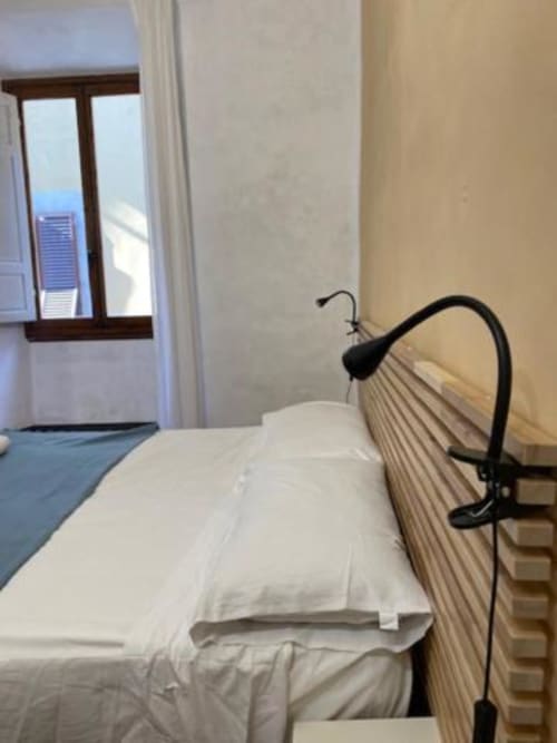 Habitación luminosa en Bronze Horse Affittacamere en Florencia con ropa de cama blanca, ventilador y ventana con vista a la ciudad