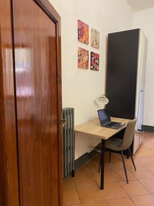 Compacto espacio de trabajo en la recepción del Bronze Horse Affittacamere en Florencia con escritorio, portátil y arte colorido en la pared