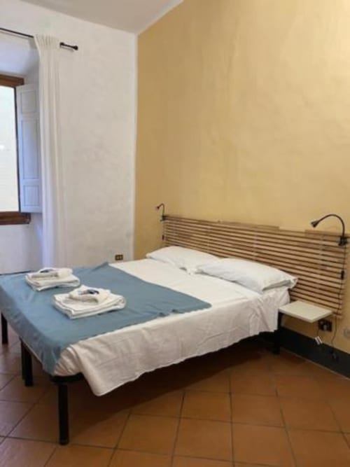 Dormitorio luminoso en Bronze Horse Affittacamere de Florencia con cama doble, almohadas blancas y paredes amarillas