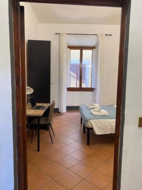 Dormitorio del Bronze Horse Affittacamere Firenze con escritorio, cama y ventana con vistas al paisaje urbano de Florencia