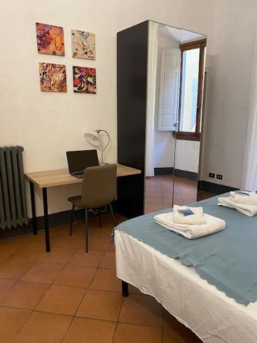 Dormitorio moderno en Bronze Horse Affittacamere de Florencia con cama, escritorio y obras de arte coloridas en las paredes