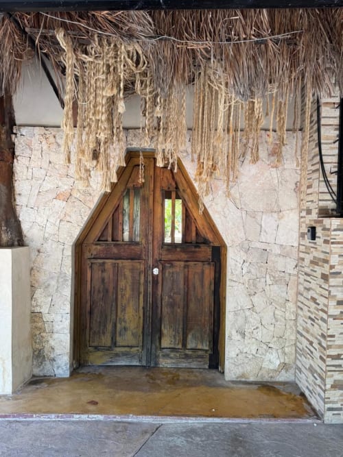 Rústicas puertas dobles de madera con tejadillo de paja en Ala Residencias Villa Tulum, Chetumal México