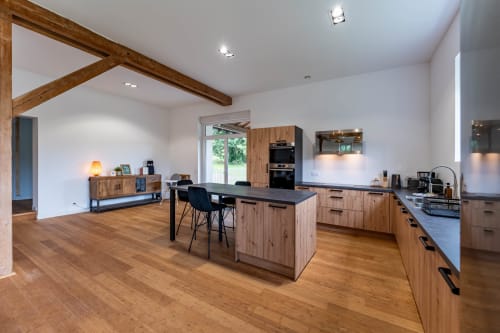 Cuisine ouverte moderne et espace de vie à Le Refuge des Brumes avec poutres en bois, îlot central et accès au jardin