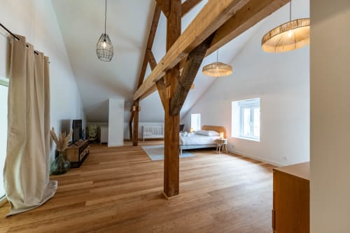Spacieuse chambre loft au Refuge des Brumes avec poutres apparentes, parquet et luminaires suspendus modernes