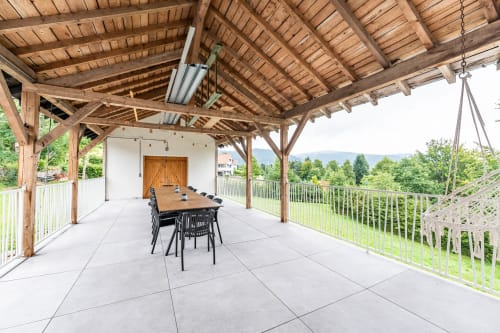 Terrasse couverte en bois avec table à manger au Refuge des Brumes, vue sur les montagnes