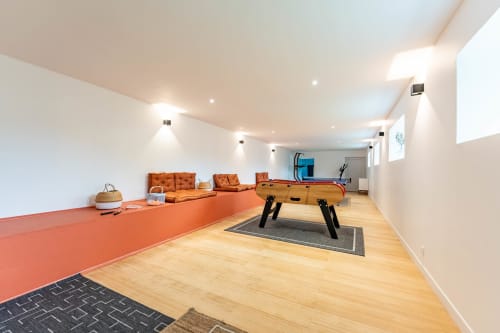 Salle de jeux moderne au Refuge des Brumes avec baby-foot, sièges orange et sol en bois