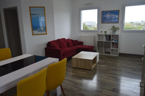Élégant séjour à la Résidence des dunes à Landéda : canapé bordeaux, chaises jaunes, table à manger et grandes ouvertures