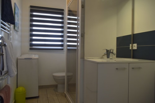 Salle de bains moderne à la Résidence des dunes, Landéda avec meuble vasque blanc, toilettes et stores à rayures