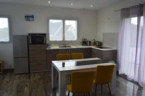 Cuisine et salle à manger modernes de l'appartement à Landéda avec chaises jaunes et vue sur le jardin