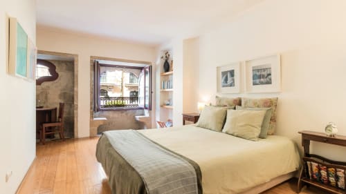 Bright Porto apartment bedroom with city view, wooden floors, queen bed with green accents, and access to terrace at