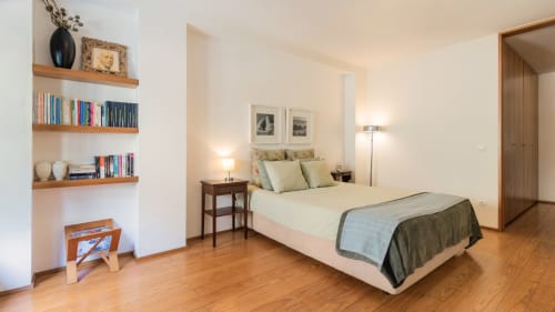 Chambre à Flowerstreet54 Porto avec étagères en bois, lit queen-size, coussins verts, table de nuit en bois et parquet.