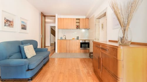 Appartement moderne à Flowerstreet54 Porto avec canapé bleu, placards de cuisine en bois et parquet dans un séjour ouvert