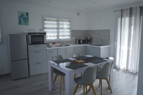 Cuisine-séjour moderne avec meubles blancs, crédence en carrelage gris et table à manger à la Résidence des dunes