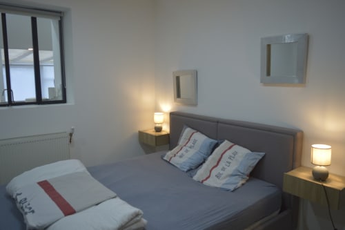 Chambre moderne à la Résidence des dunes à Landéda avec lit double, tête de lit grise, lampes de chevet, miroirs et radiateur