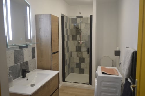 Salle de bains moderne à la Résidence des dunes avec douche carrelée, vasque et meubles en bois à Landéda