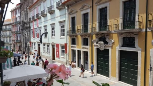 Rue historique colorée de Porto avec bâtiments jaunes et rouges, balcons et fleurs roses, montrant l'appartement Flowerstreet54