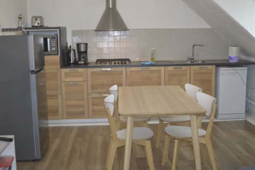 Cuisine et salle à manger modernes de l'appartement de Landéda avec meubles en bois, table à manger et électroménagers en acier inoxydable