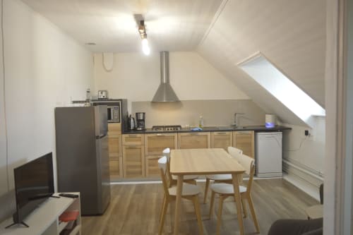 Cuisine ouverte et salle à manger de l'appartement à Landéda avec table en bois, électroménagers modernes et puits de lumière